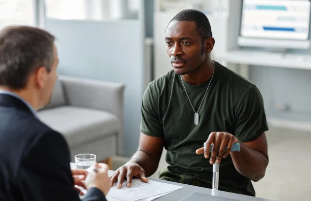 Young adult african american soldier with walking stick talking about his problems to psychologist d