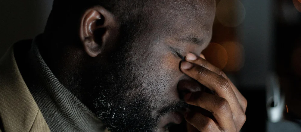 Face of exhausted african businessman touching his closed eyes