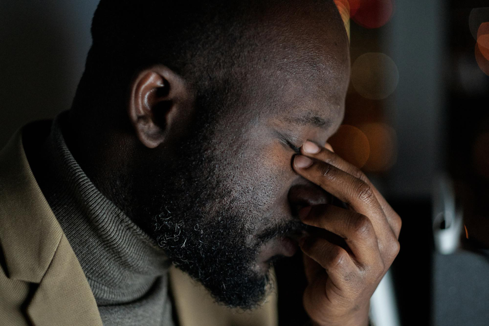 Face of exhausted african businessman touching his closed eyes