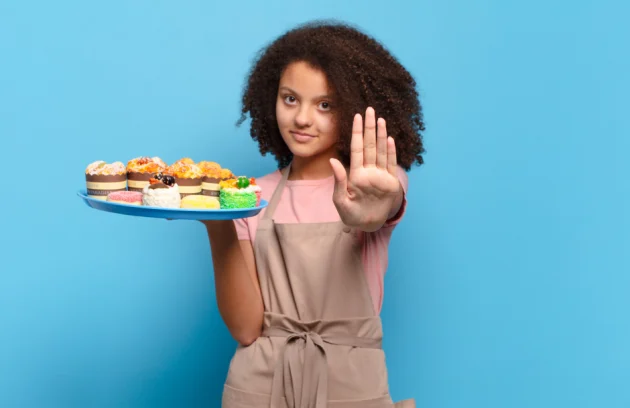 Pretty afro teenager looking serious, stern, displeased and angry showing open palm making stop gesture. humorous baker concept