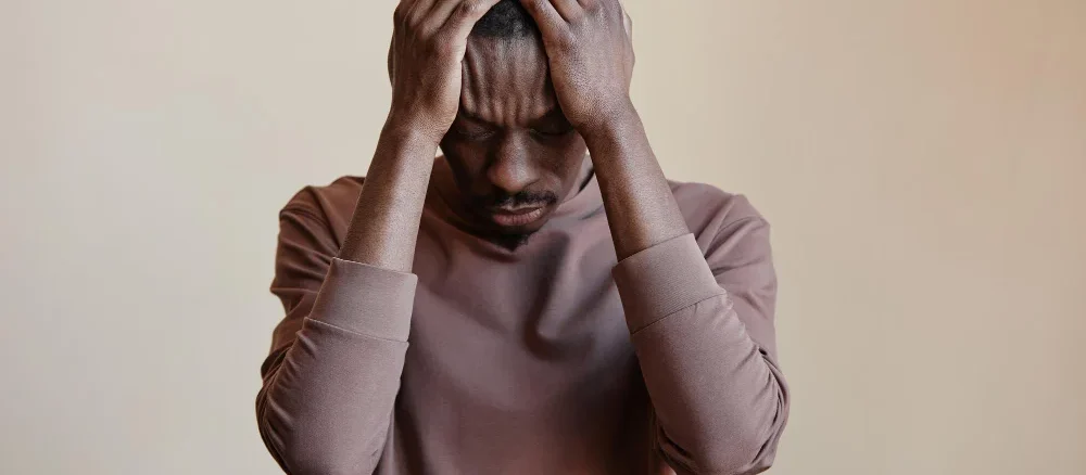 Black man holding head in hands felling Depression