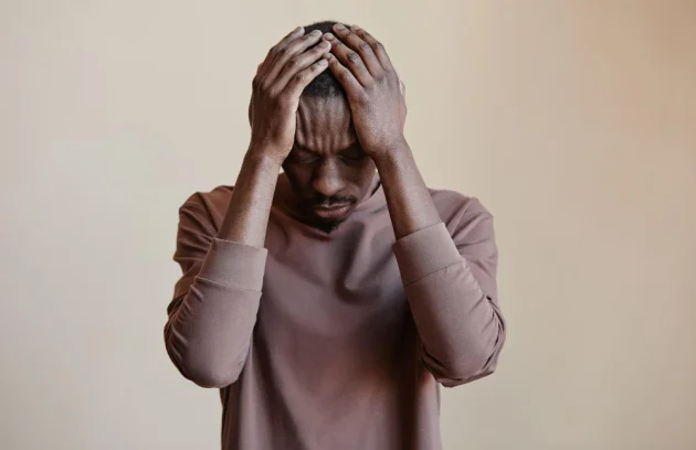 Black man holding head in hands felling Depression