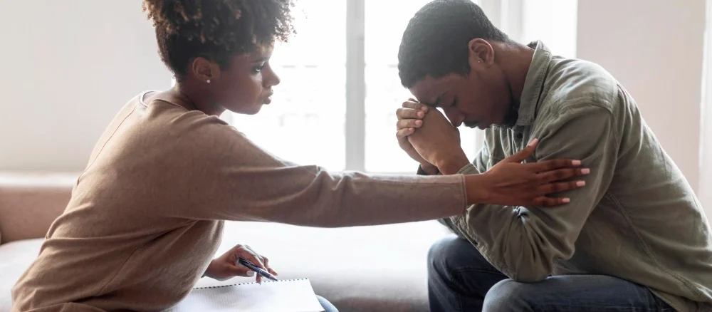 Black woman psychologist comforting man patient with Healing from Trauma side view
