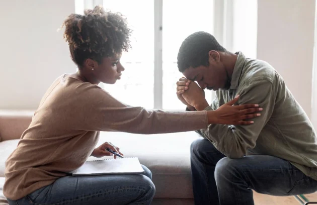 Black woman psychologist comforting man patient with Healing from Trauma side view