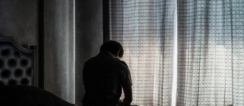 man with depression sitting on bed