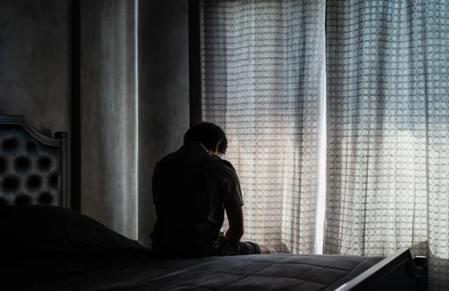man with depression sitting on bed