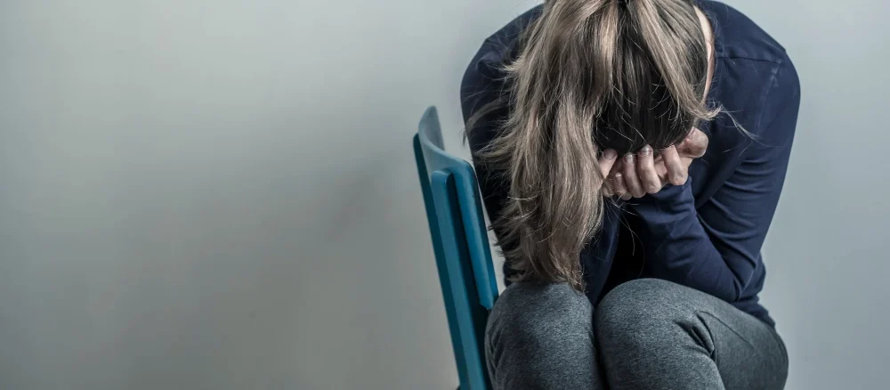 Depressive and desperate girl sits on a chair. Sad young woman