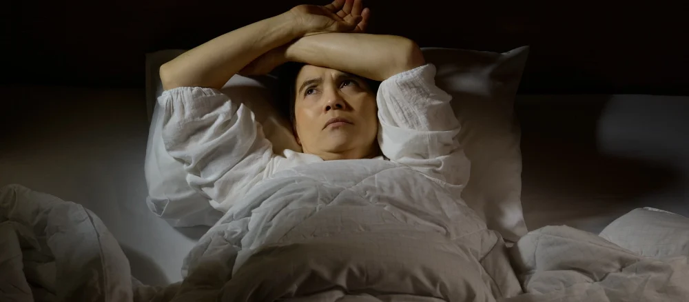 Woman with insomnia lying in bed with open eyes