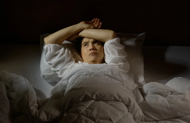 Woman with insomnia lying in bed with open eyes